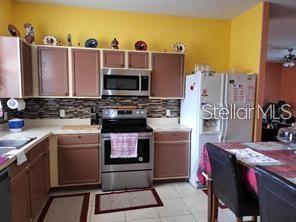 1107 Dartford Dr, Kissimmee, FL 34758 - kitchen with appliances with stainless steel finishes, tasteful backsplash, light tile patterned floors, and ceiling fan