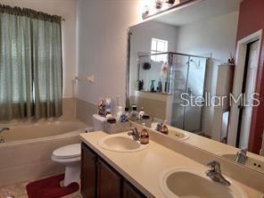 1107 Dartford Dr, Kissimmee, FL 34758 - bathroom with a garden tub, a stall shower, toilet, and double vanity