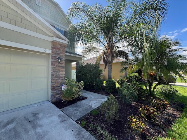 3003 Cobham Rd, Kissimmee, FL 34758 - view of side of home with stone siding, a garage, and stucco siding