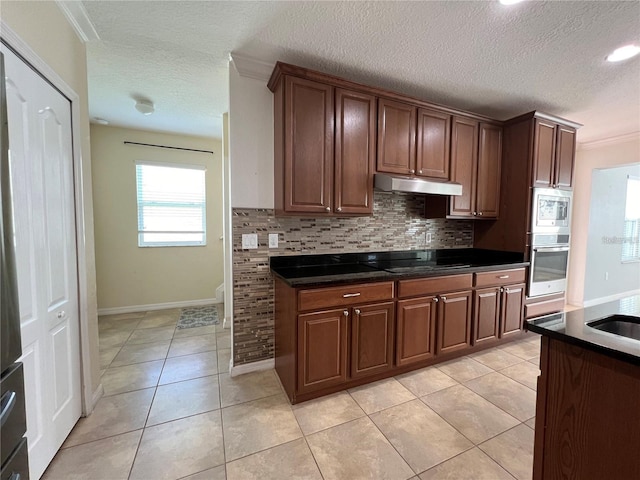 3003 Cobham Rd, Kissimmee, FL 34758 - kitchen with stainless steel appliances, under cabinet range hood, backsplash, dark countertops, and a textured ceiling