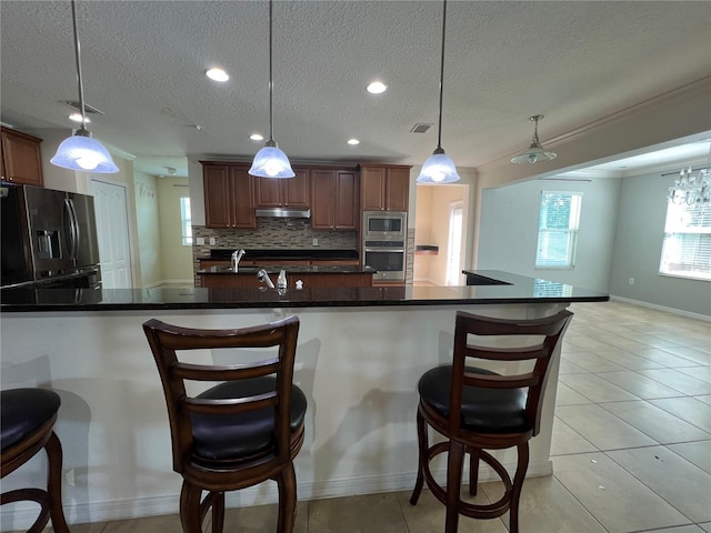 3003 Cobham Rd, Kissimmee, FL 34758 - kitchen featuring appliances with stainless steel finishes, healthy amount of natural light, crown molding, a kitchen bar, and under cabinet range hood