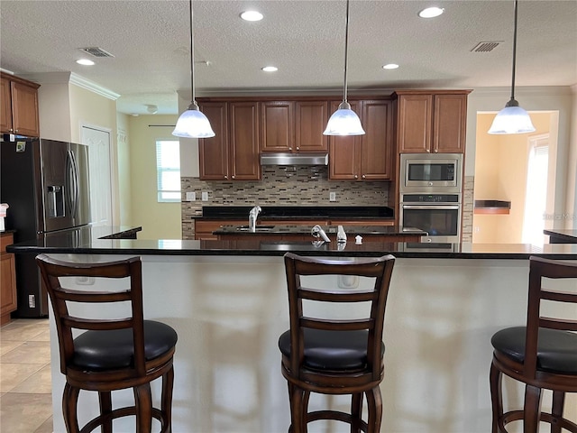 3003 Cobham Rd, Kissimmee, FL 34758 - kitchen with stainless steel appliances, a kitchen bar, tasteful backsplash, under cabinet range hood, and a textured ceiling