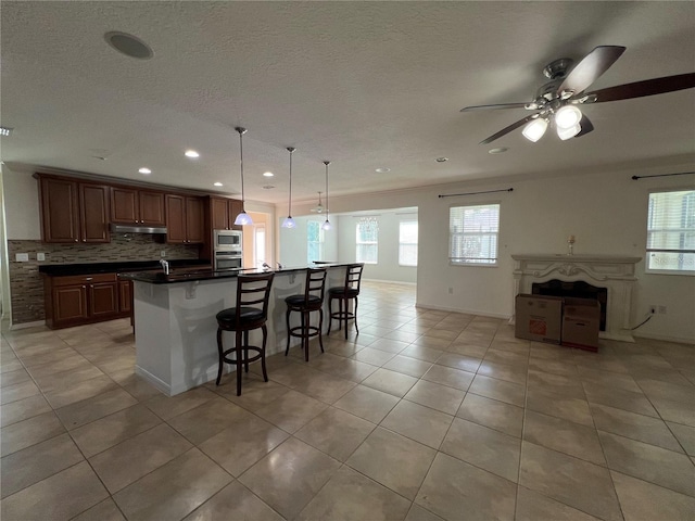 3003 Cobham Rd, Kissimmee, FL 34758 - kitchen with stainless steel appliances, under cabinet range hood, light tile patterned floors, dark countertops, and open floor plan