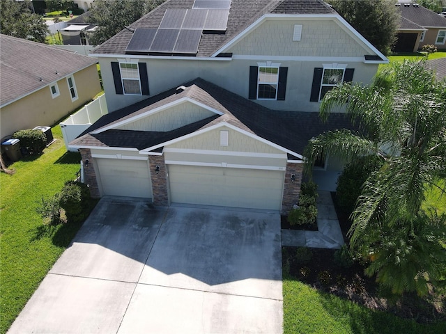 3003 Cobham Rd, Kissimmee, FL 34758 - view of front of home featuring stone siding, a shingled roof, concrete driveway, and roof mounted solar panels
