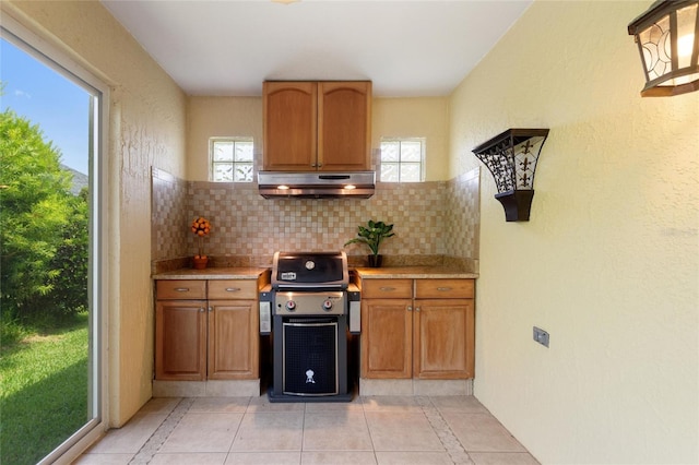 1258 Donalds Pl, The Villages, FL 32162 - kitchen with under cabinet range hood, light countertops, backsplash, light tile patterned floors, and healthy amount of natural light