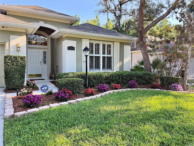 property entrance with a lawn, stucco siding, a shingled roof, and a garage