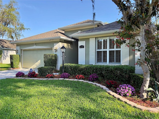 single story home featuring a garage, driveway, a front yard, and stucco siding
