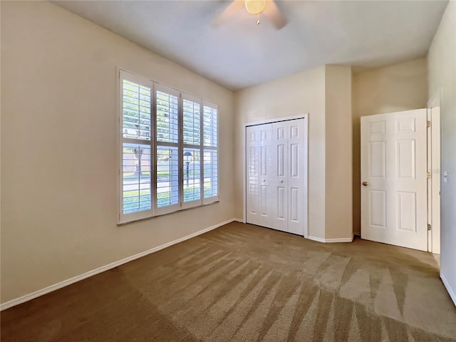 unfurnished bedroom featuring baseboards, carpet flooring, a closet, and ceiling fan