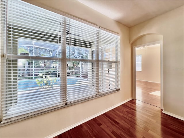 spare room featuring baseboards and wood finished floors
