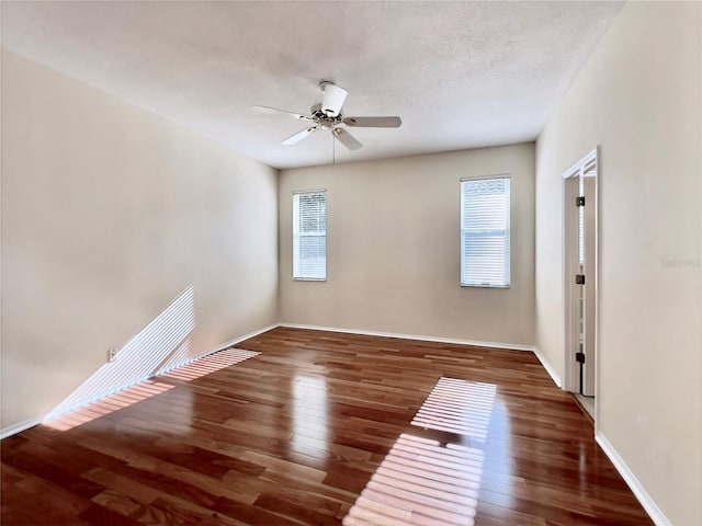 spare room featuring wood finished floors, a ceiling fan, and baseboards