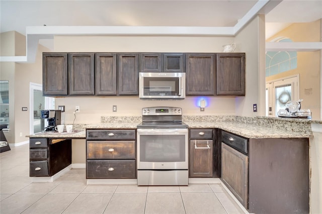 3211 Countryside View Dr, Saint Cloud, FL 34772 - kitchen with appliances with stainless steel finishes, dark brown cabinetry, light tile patterned flooring, and light stone countertops