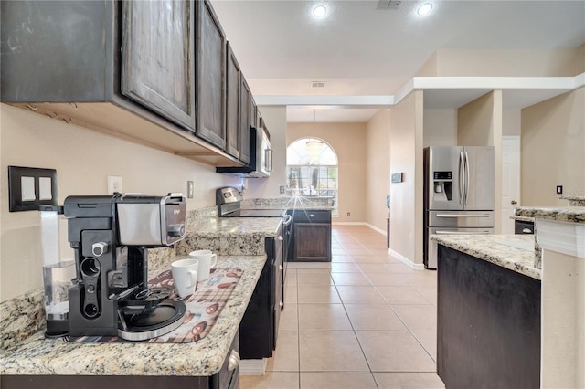 3211 Countryside View Dr, Saint Cloud, FL 34772 - kitchen with appliances with stainless steel finishes, light tile patterned floors, light stone counters, dark brown cabinetry, and baseboards
