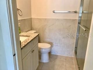 1309 N Thacker Ave, Kissimmee, FL 34741 - full bathroom with tile walls, a stall shower, vanity, tile patterned floors, and a wainscoted wall