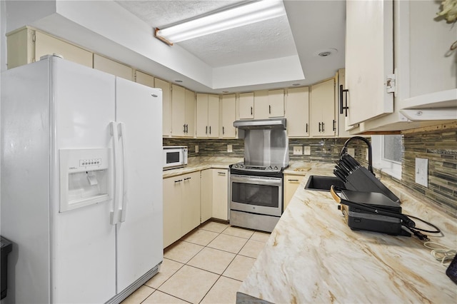 1408 Polk City Rd, Haines City, FL 33844 - kitchen featuring white appliances, cream cabinetry, under cabinet range hood, light countertops, and a textured ceiling