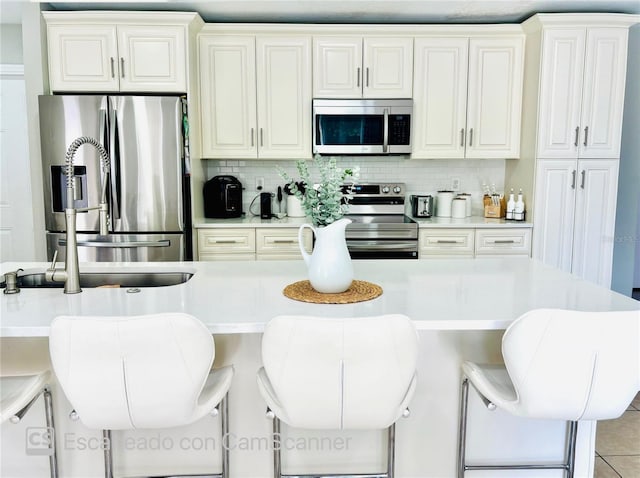 467 Martigues Dr, Kissimmee, FL 34759 - kitchen with stainless steel appliances, light countertops, a kitchen breakfast bar, backsplash, and light tile patterned floors