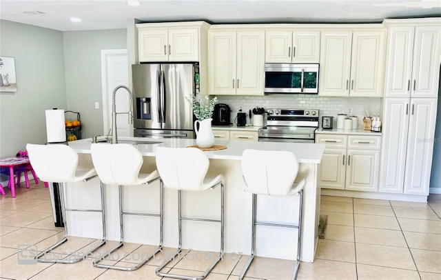467 Martigues Dr, Kissimmee, FL 34759 - kitchen featuring stainless steel appliances, a breakfast bar area, light countertops, backsplash, and light tile patterned flooring