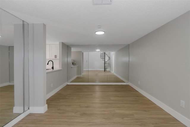 5151 Puritan Cir Unit 1022, Tampa, FL 33617 - hall featuring light wood-style flooring, baseboards, a textured ceiling, and a sink
