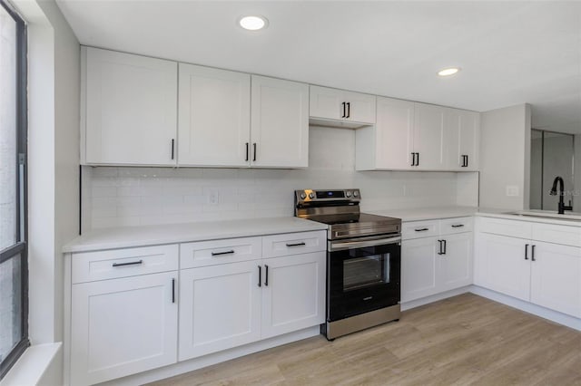 5151 Puritan Cir Unit 1022, Tampa, FL 33617 - kitchen with electric range, a sink, light countertops, white cabinets, and recessed lighting