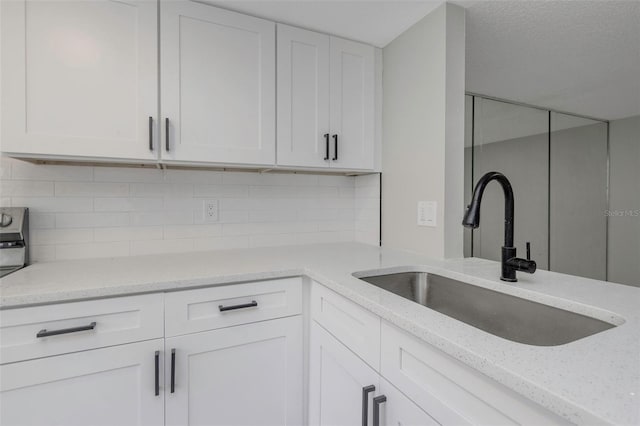 5151 Puritan Cir Unit 1022, Tampa, FL 33617 - kitchen featuring a sink, white cabinets, light stone countertops, and tasteful backsplash