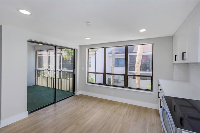 5151 Puritan Cir Unit 1022, Tampa, FL 33617 - kitchen with stainless steel electric range oven, light wood finished floors, white cabinets, light countertops, and tasteful backsplash