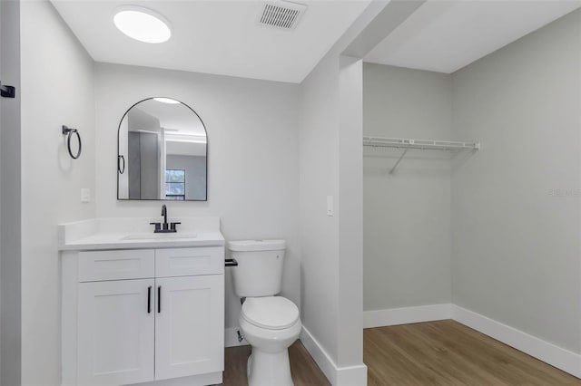 5151 Puritan Cir Unit 1022, Tampa, FL 33617 - bathroom with wood finished floors, toilet, vanity, baseboards, and a spacious closet
