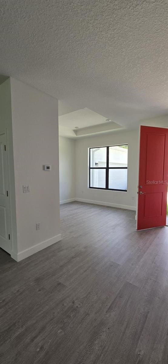 spare room featuring dark wood-type flooring, baseboards, and a textured ceiling
