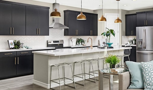 kitchen with appliances with stainless steel finishes, dark cabinetry, a sink, light wood-style floors, and light countertops