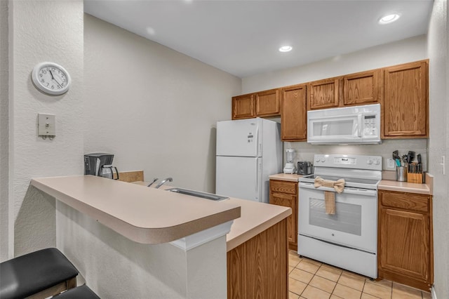 2614 Lodi Cir Unit 106, Kissimmee, FL 34746 - kitchen featuring white appliances, a sink, a peninsula, light tile patterned floors, and brown cabinets