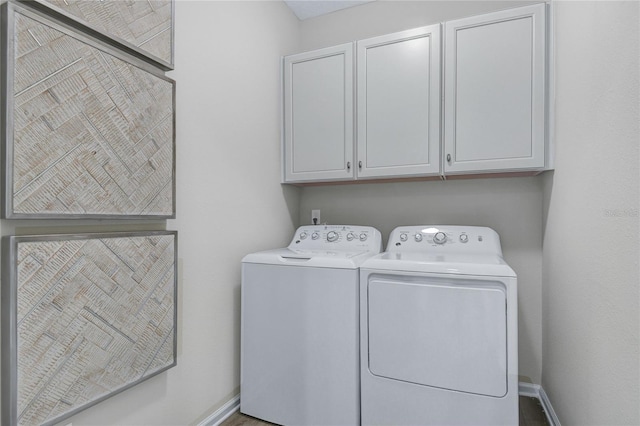 washroom featuring washing machine and dryer, cabinet space, and baseboards