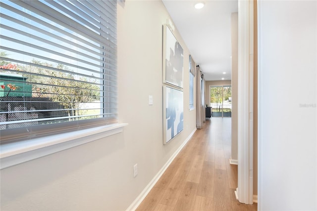 hallway featuring light wood-style flooring, baseboards, and recessed lighting