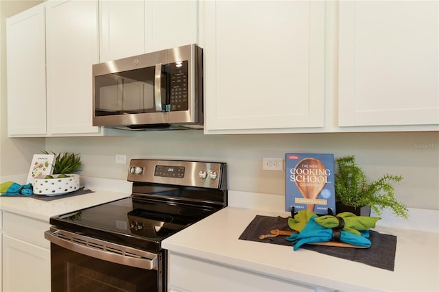kitchen featuring stainless steel appliances, white cabinets, and light countertops