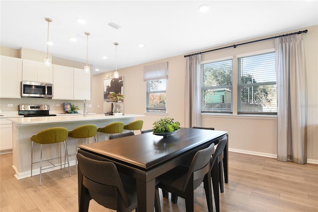 dining room with light wood-style floors, recessed lighting, and baseboards