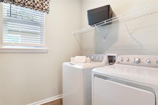 washroom with washing machine and dryer, baseboards, and wood finished floors