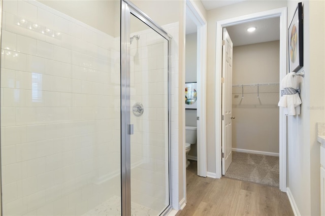 bathroom with a stall shower, toilet, and wood finished floors