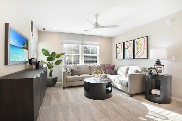 living room with light carpet, a ceiling fan, and baseboards