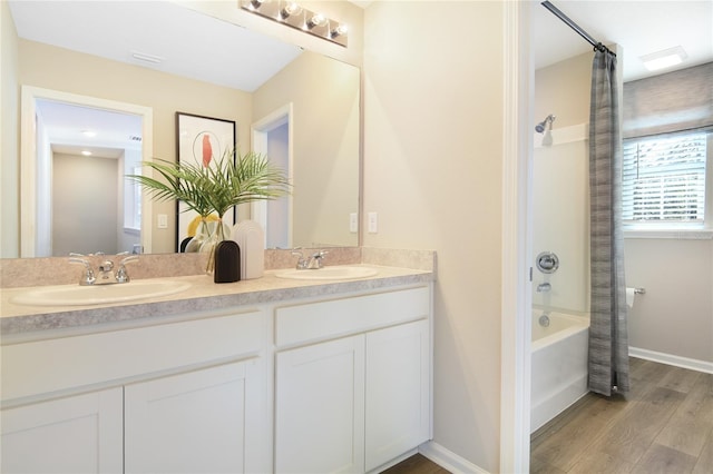 bathroom with wood finished floors, double vanity, shower / bath combo with shower curtain, and baseboards