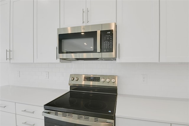 3723 Malad Way, Tavares, FL 32778 - kitchen with stainless steel appliances, light countertops, white cabinetry, and decorative backsplash