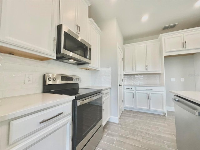 1001 Umbria Dr, Poinciana, FL 34759 - kitchen featuring stainless steel appliances, white cabinets, decorative backsplash, and light countertops