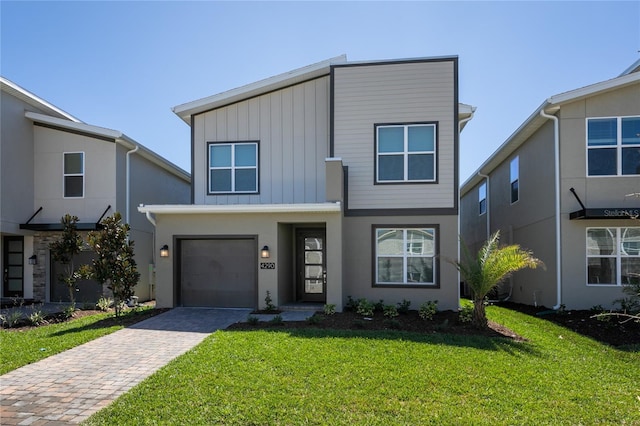 4290 Paragraph Dr, Kissimmee, FL 34746 - view of front facade with decorative driveway, a front lawn, a garage, board and batten siding, and stucco siding