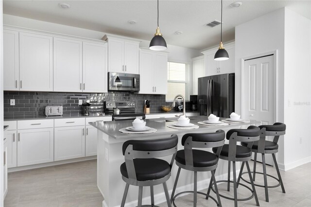 4290 Paragraph Dr, Kissimmee, FL 34746 - kitchen with appliances with stainless steel finishes, backsplash, a center island with sink, a breakfast bar area, and white cabinets