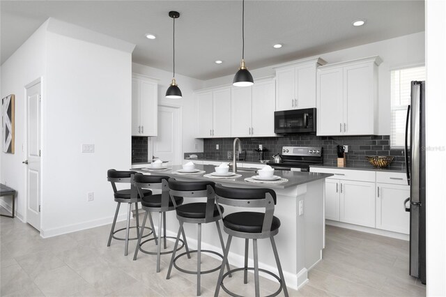 4290 Paragraph Dr, Kissimmee, FL 34746 - kitchen featuring stainless steel appliances, dark countertops, backsplash, a kitchen breakfast bar, and a kitchen island with sink