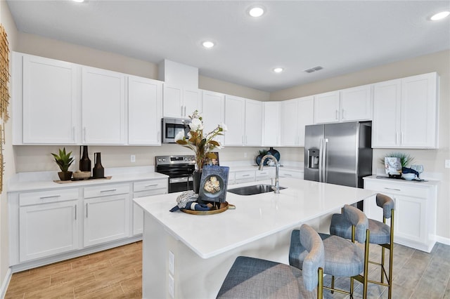9253 Players Dr, Weeki Wachee, FL 34613 - kitchen with a sink, appliances with stainless steel finishes, a kitchen bar, light wood-style floors, and recessed lighting