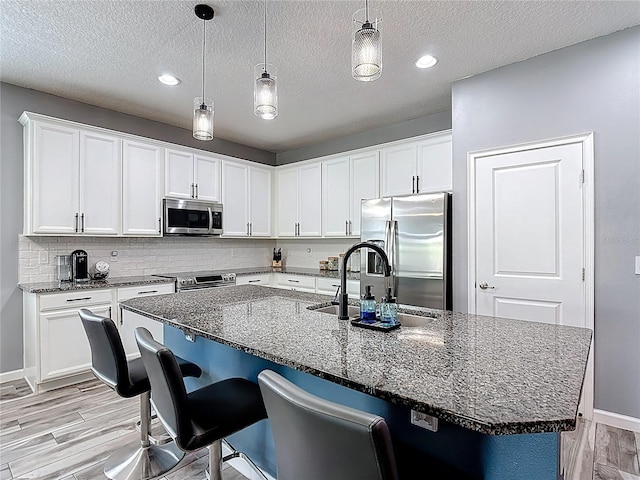 140 Trinity Ridge Cir, Davenport, FL 33897 - kitchen featuring stainless steel appliances, light wood-style floors, dark stone countertops, a textured ceiling, and recessed lighting