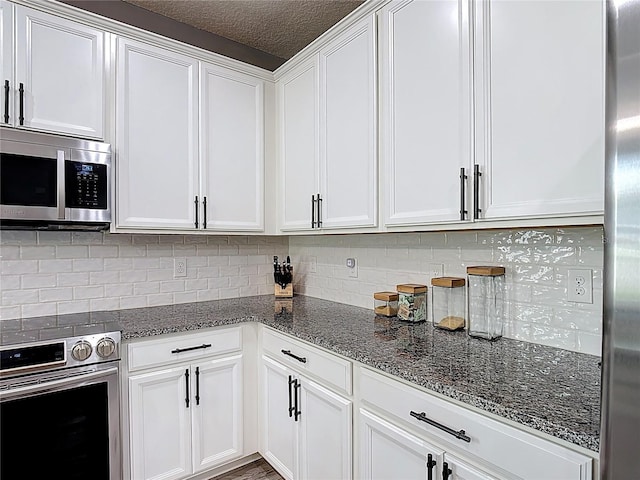 140 Trinity Ridge Cir, Davenport, FL 33897 - kitchen with appliances with stainless steel finishes, white cabinets, dark stone counters, backsplash, and a textured ceiling