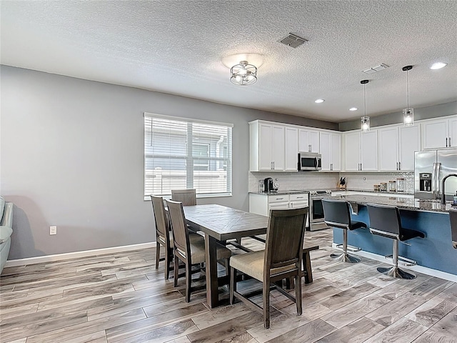 140 Trinity Ridge Cir, Davenport, FL 33897 - dining area featuring light wood-style floors, a textured ceiling, recessed lighting, and baseboards