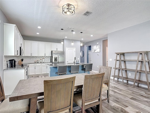 140 Trinity Ridge Cir, Davenport, FL 33897 - dining room featuring light wood-style flooring, recessed lighting, a textured ceiling, and baseboards