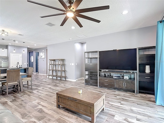 140 Trinity Ridge Cir, Davenport, FL 33897 - living room with ceiling fan, a textured ceiling, light wood-style floors, and baseboards