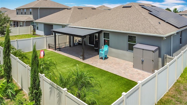 140 Trinity Ridge Cir, Davenport, FL 33897 - rear view of property with roof with shingles, a patio area, stucco siding, and roof mounted solar panels
