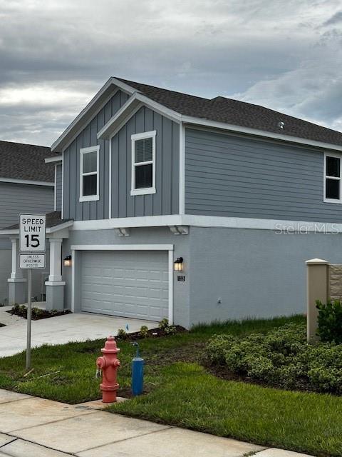 view of side of property featuring board and batten siding, an attached garage, and concrete driveway
