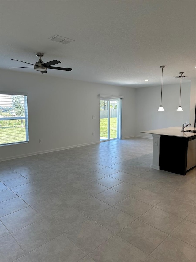 unfurnished living room featuring a sink, a ceiling fan, baseboards, and light tile patterned floors